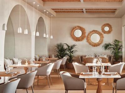 Restaurant d'hôtel élégant avec miroirs ronds, tables en bois et chaises confortables.