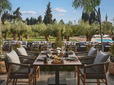 Terrasse de restaurant avec table dressée offrant une vue sur une piscine et des palmiers.