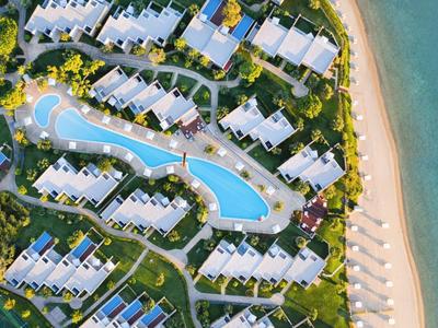 Luftaufnahme eines Resorts mit Pool und direkt angrenzendem Sandstrand am Meer.