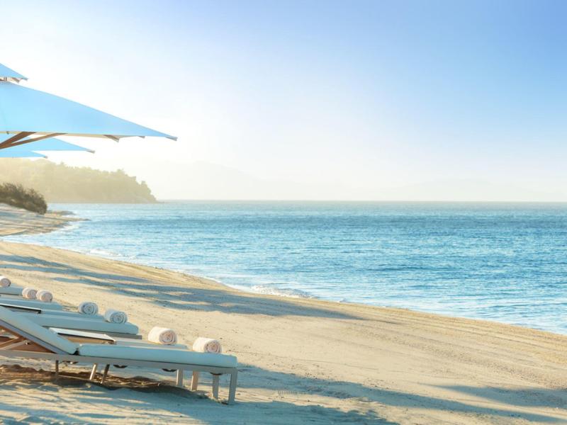 Leerer Strand mit Liegestühlen und Sonnenschirm bei klarem Himmel