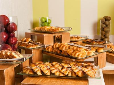 Snídaňový bufet s croissanty, jablky, chlebem a cereáliemi v útulném prostředí