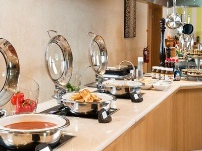 Bufet s teplými jídly v moderní hotelové restauraci s nerezovými nádobami.