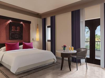 Elegantes Schlafzimmer mit großem Bett, lila Kissen, dunklen Vorhängen und Balkonzugang.