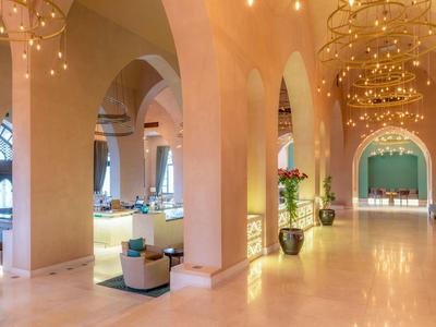 Großer heller Saal mit hohen Bögen, modernen Sitzgruppen und eleganten Kronleuchtern.