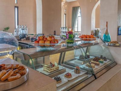 Moderne Cafetheke mit Glasvitrinen, Gebäck, Obst und Kuchen in freundlichem Innenraum.