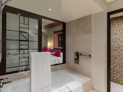 Modernes Badezimmer mit weißer Badewanne, großen Spiegeln und beiger Mosaikwand in Dusche.