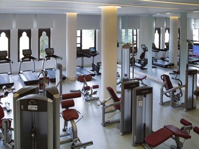 Moderne Fitnessstudio mit vielen Trainingsgeräten und Spiegeln an den Wänden.