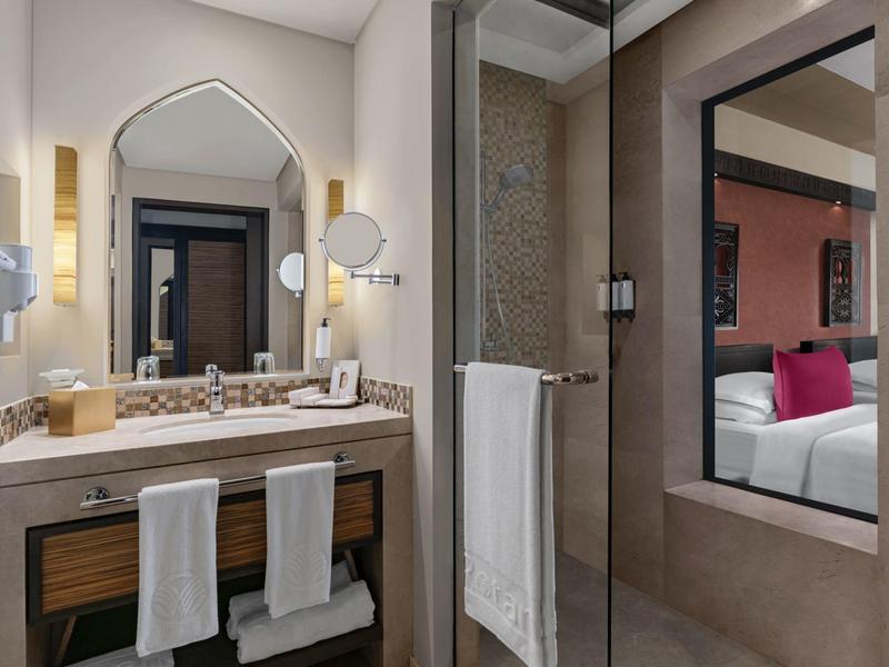 Modernes Badezimmer mit großem Spiegel, Waschbecken, warmem Licht und Handtüchern an der Ablage.