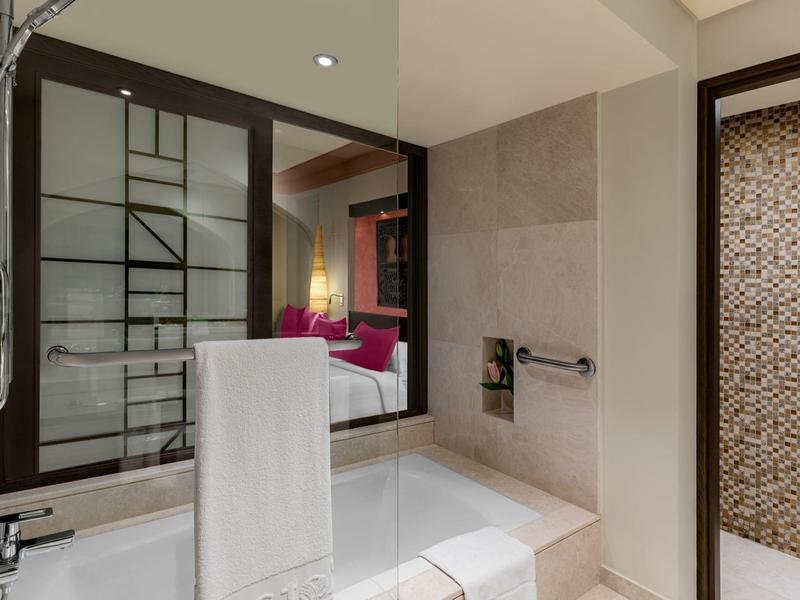 Modernes Badezimmer mit weißer Badewanne, großen Spiegeln und beiger Mosaikwand in Dusche.