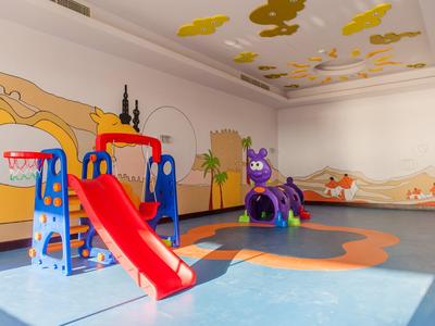 Bunte Kinderspielecke mit Rutsche, Klettergerüst und Tierfiguren auf blauem Bodenbelag.