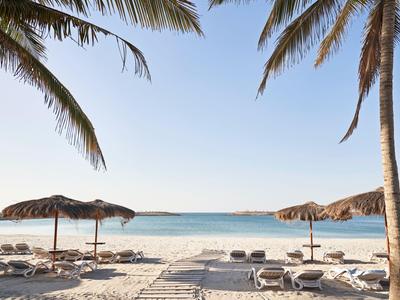 Spiaggia con lettini e ombrelloni di foglie di palma sotto un cielo azzurro