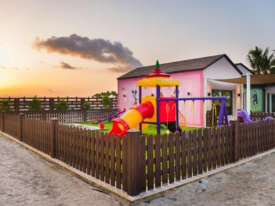 Parco giochi per bambini con scivoli davanti a case colorate al tramonto