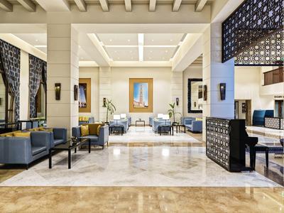 Großer, heller Lounge-Bereich mit Marmorfußboden, modernen Sesseln und dekorativen Trennwänden.