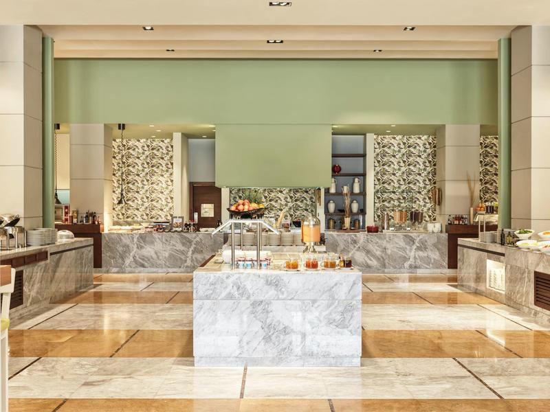 Ein heller Spa-Bereich mit Marmor, Holzfußboden, grüner Wand und dekorativen Elementen.