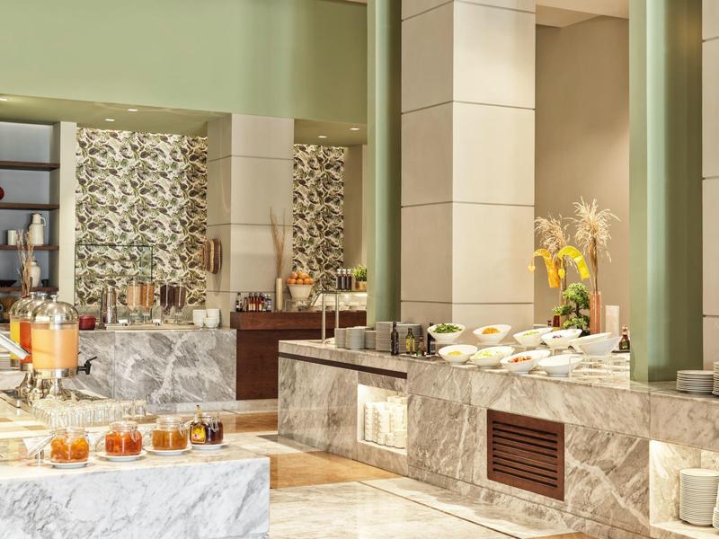 Modernes Buffet mit Marmortheke, frischem Gebäck, Saft und dekorativen Blumenarrangements.