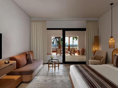 Modern hotelkamer met bed, bank, fauteuil en terras met uitzicht op zwembad