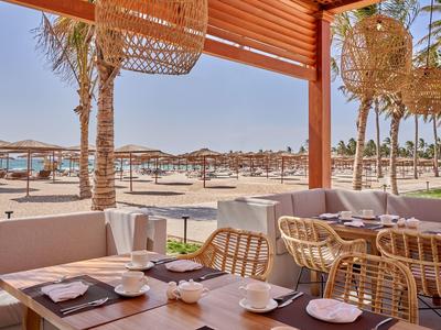 Accogliente beach bar con sedie in vimini e vista sulla spiaggia sabbiosa e sul mare.