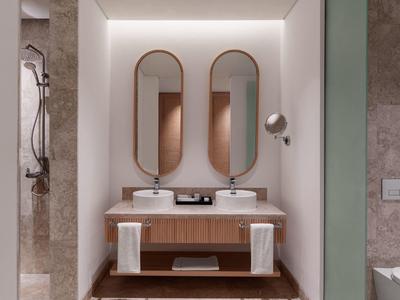 Bagno moderno con due specchi ovali, lavandini e mobili in legno.