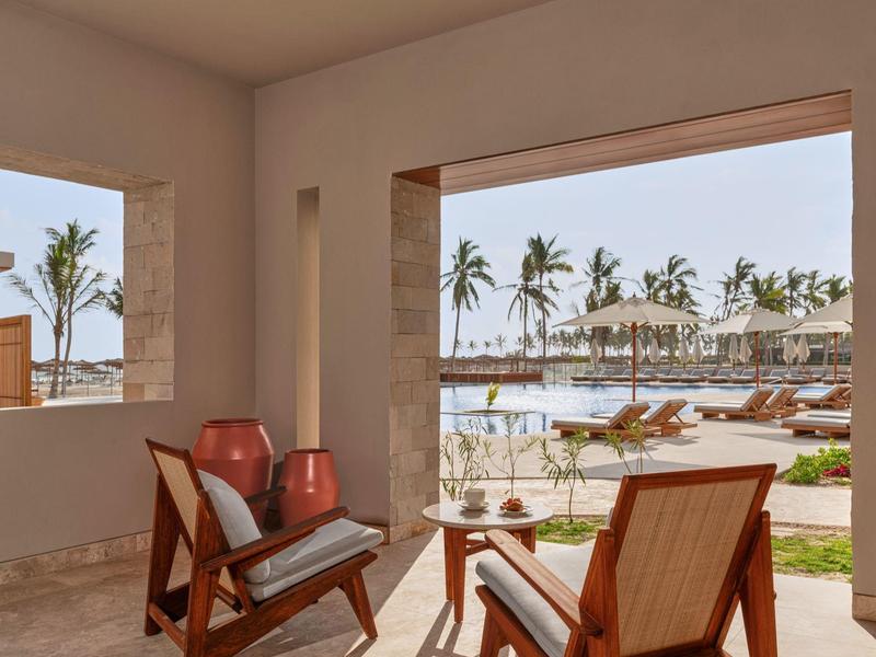 Accogliente area salotto con vista su piscina e palme in un hotel.