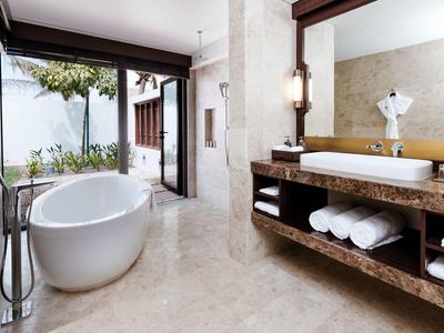 Modern bathroom with freestanding bathtub and large windows overlooking a garden.