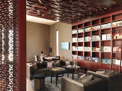 Moderner Hotel-Lounge-Bereich mit komfortablen Sofas und wandfüllendem Bücherregal.