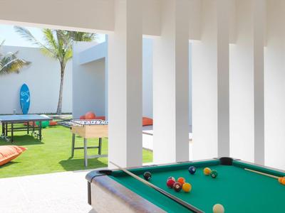 View from a covered area onto a terrace with a pool table and a table tennis table in the garden.