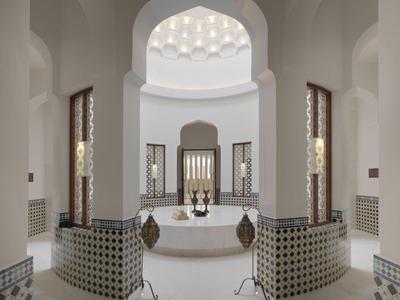 Luxurious Turkish hammam with circular marble bath and intricately decorated walls.