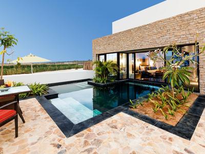 Modern house with pool, terrace, and large glass facade under clear sky.