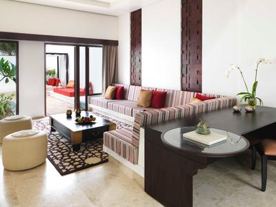 Modern lounge with sofa, coffee table, ottomans, and desk in bright, open space.