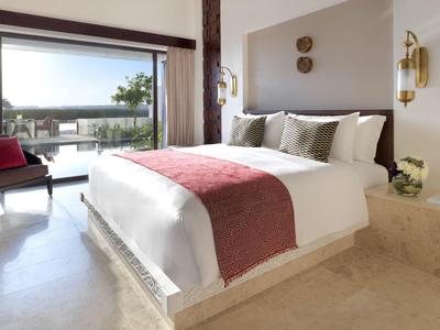 Bright bedroom with large bed, red accents, and terrace view.