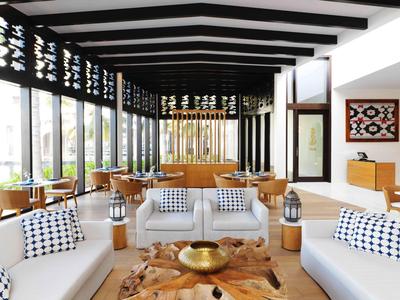 Moderner, heller Lounge-Bereich mit weißen Sofas und großen Fensterfronten.