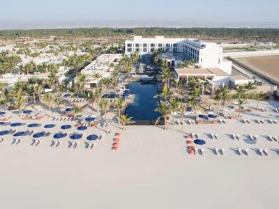 Beach resort with pools and sun umbrellas on sandy beach.