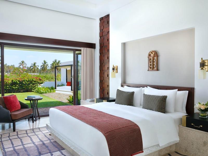 Bright hotel room with large bed and view of garden with pool.