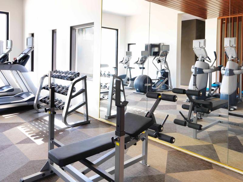 Bright hotel gym with treadmills and weight machines in a modern design.