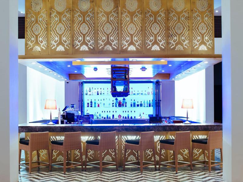 Elegant bar with decorative gold-patterned upper frame and rows of bar stools.
