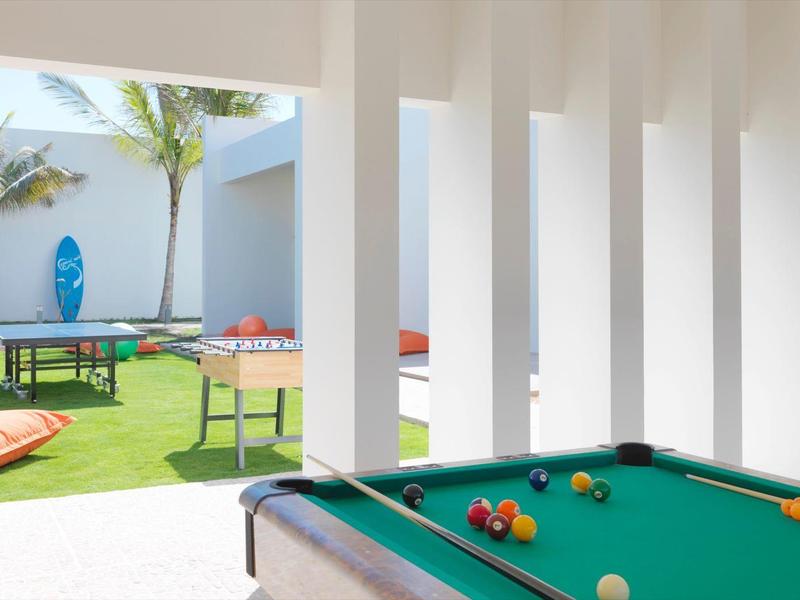 View from a covered area onto a terrace with a pool table and a table tennis table in the garden.