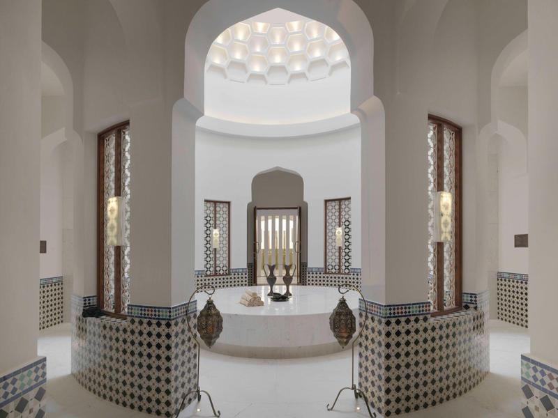 Luxurious Turkish hammam with circular marble bath and intricately decorated walls.