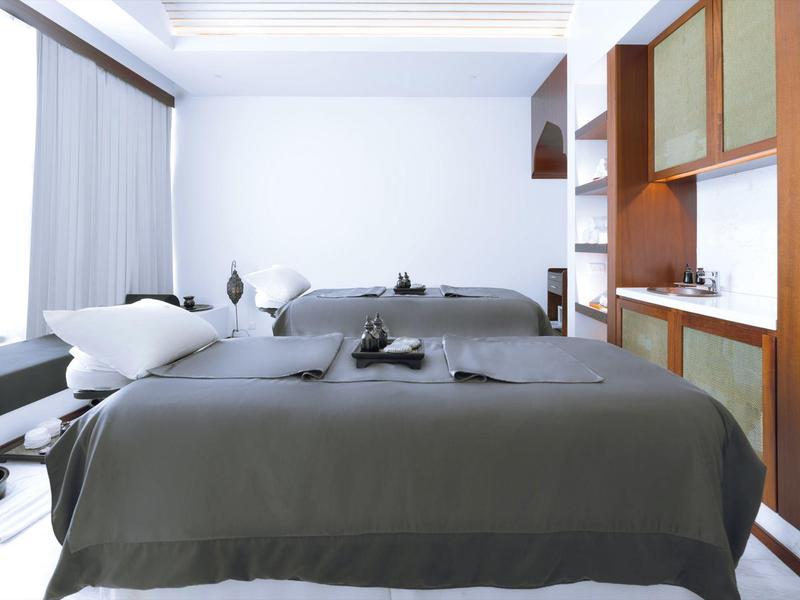 Modern treatment room with two massage tables and white walls.