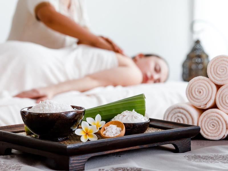 Relaxing massage scene with aromatherapy and stacked towels in spa setting.