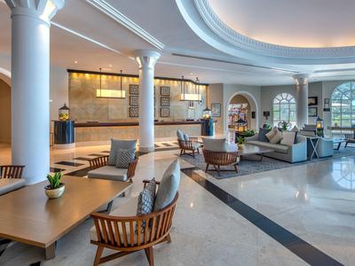 Großer, heller Lobbybereich mit modernen Sitzgruppen, runden Säulen und warmen Holzakzenten.