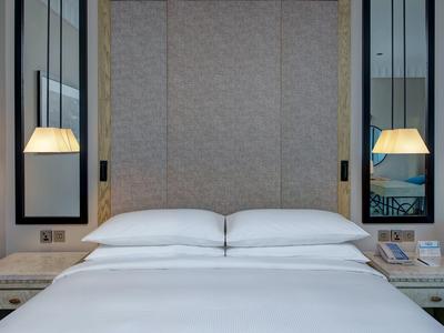 Modernes Schlafzimmer mit großem, weiß bezogenem Bett, grauem Kopfteil und zwei hängenden Lampen.