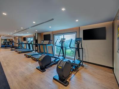 Moderne fitnessruimte met cardioapparaten en houten vloeren in een hotel.