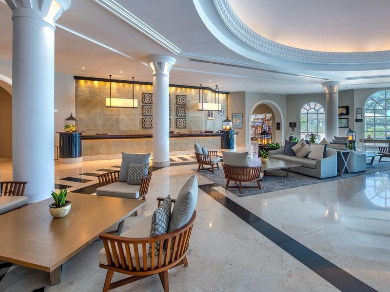 Großer, heller Lobbybereich mit modernen Sitzgruppen, runden Säulen und warmen Holzakzenten.