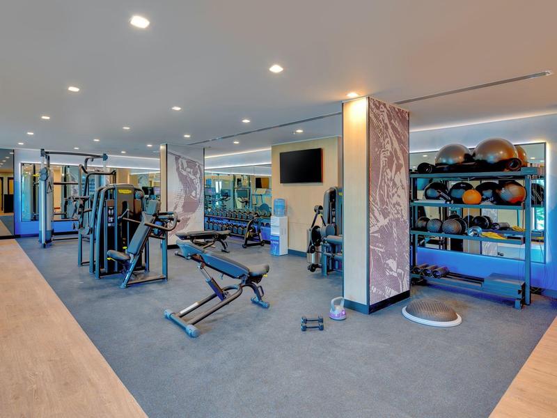 Moderner Fitnessraum mit Geräten und Hanteln in einem Hotel.