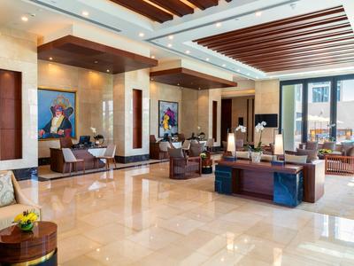 Jasna lobby hotelowa z wygodnymi miejscami do siedzenia, dużymi oknami i nowoczesnym oświetleniem.