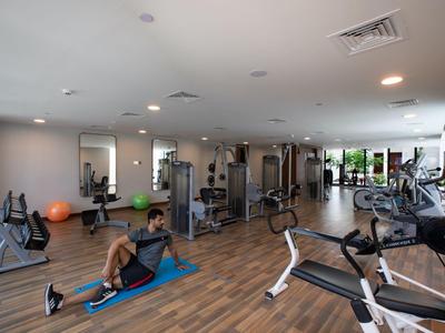 Siłownia z różnymi urządzeniami do ćwiczeń i osobą na macie.