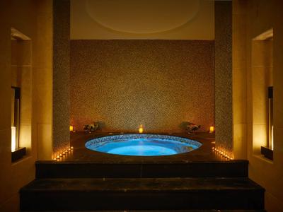 Helles, rundes Whirlpool-Becken mit blauer Beleuchtung in dunklem, luxuriösem Raum mit warmem Licht.