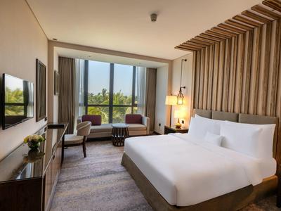 Modernes Hotelzimmer mit großem Bett, Sitzbereich am Fenster und warmem, holzvertäfeltem Design.