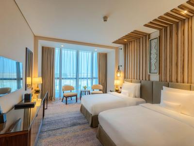 Nowoczesny pokój hotelowy z dwoma pojedynczymi łóżkami, drewnianymi panelami i telewizorem.