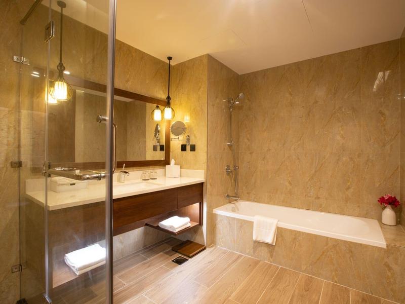 Modernes Badezimmer mit Badewanne, beleuchtetem Spiegel und einer Glasdusche.